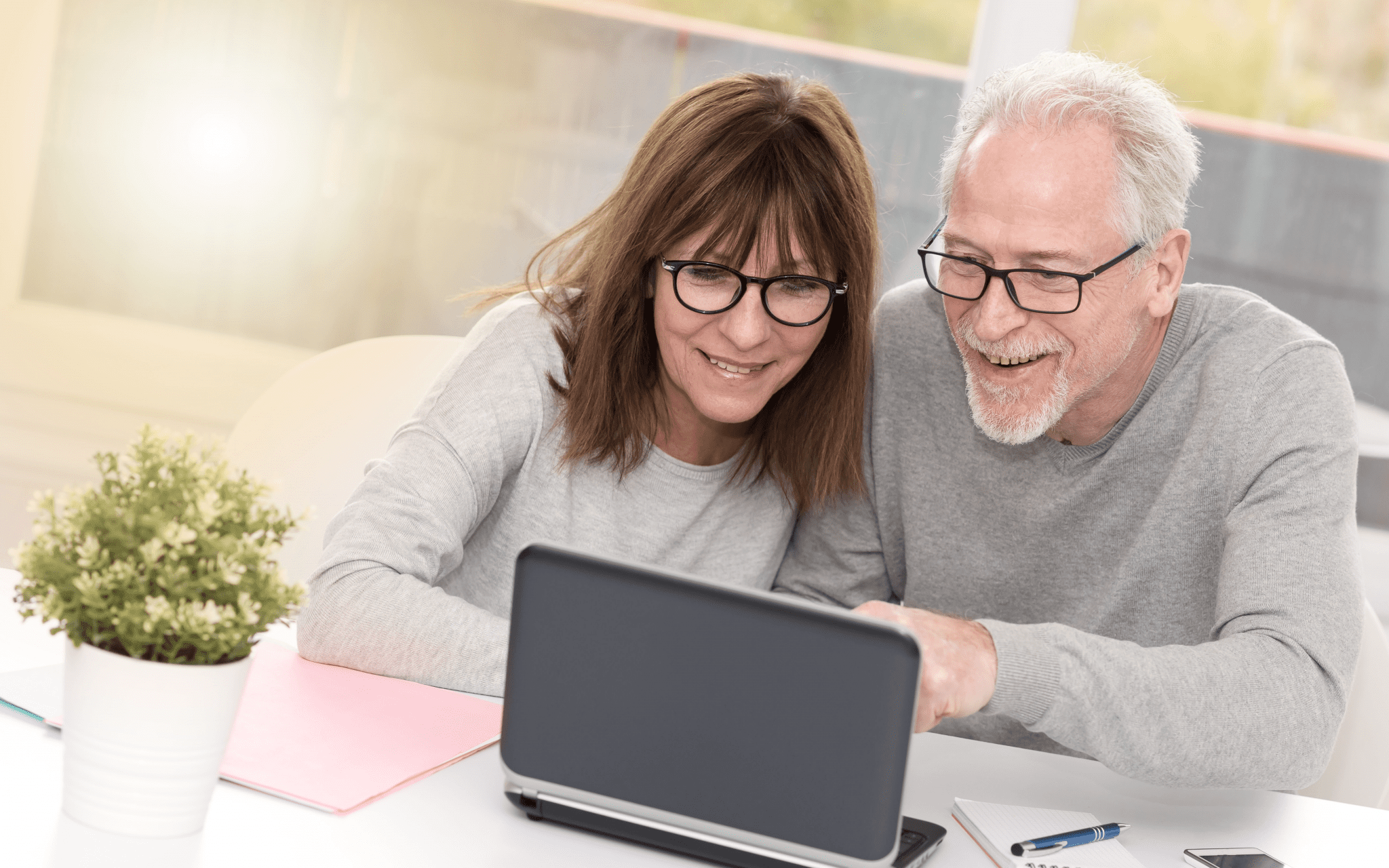 Couple happily looking at their asbestos trust funds on a laptop.