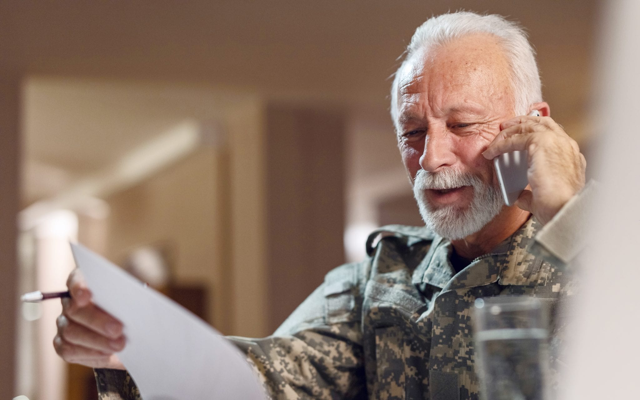 Veteran on cell phones talks to VA Hospital while looking at a document.