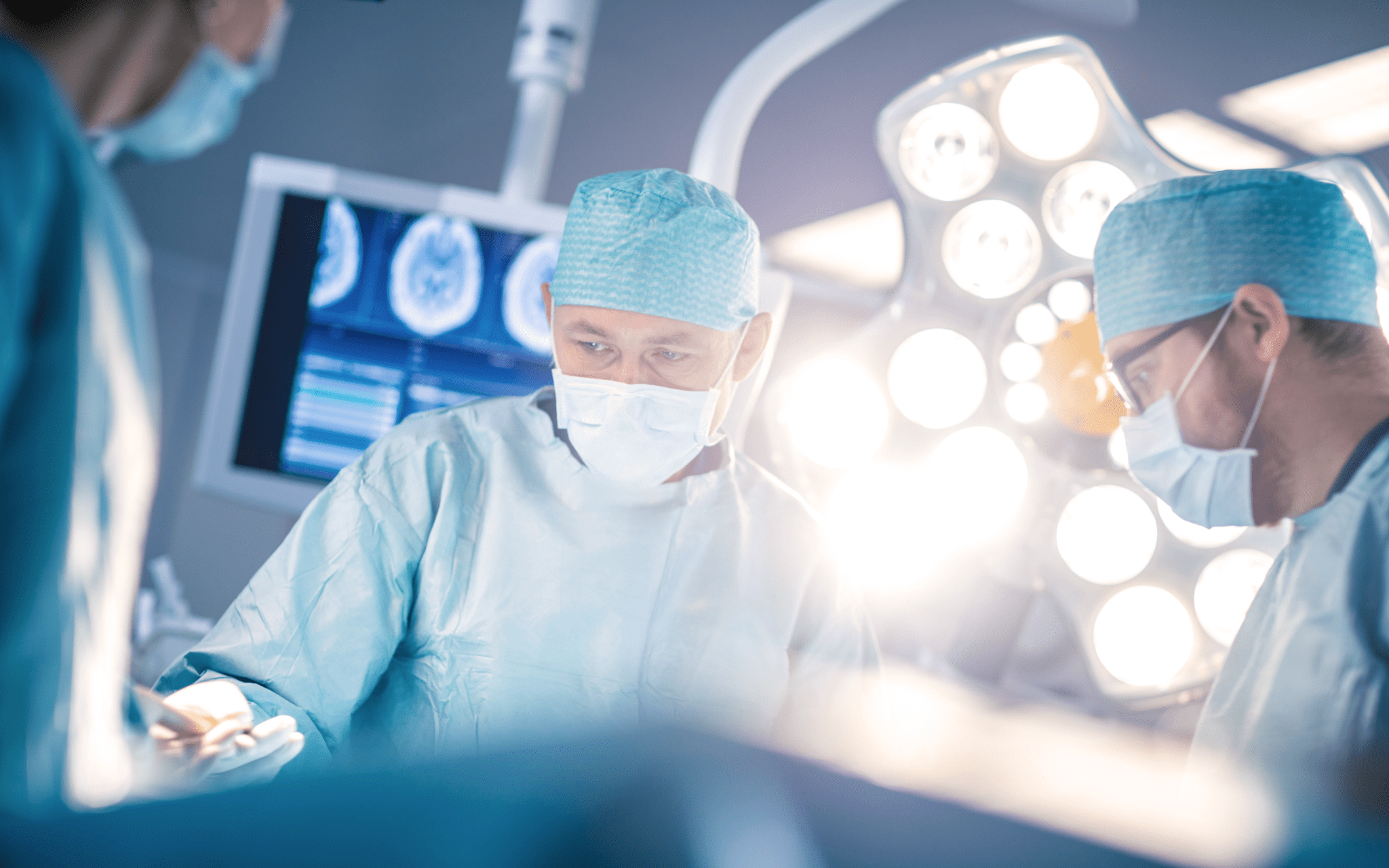 Three surgeons perform surgery on someone in an operating room.