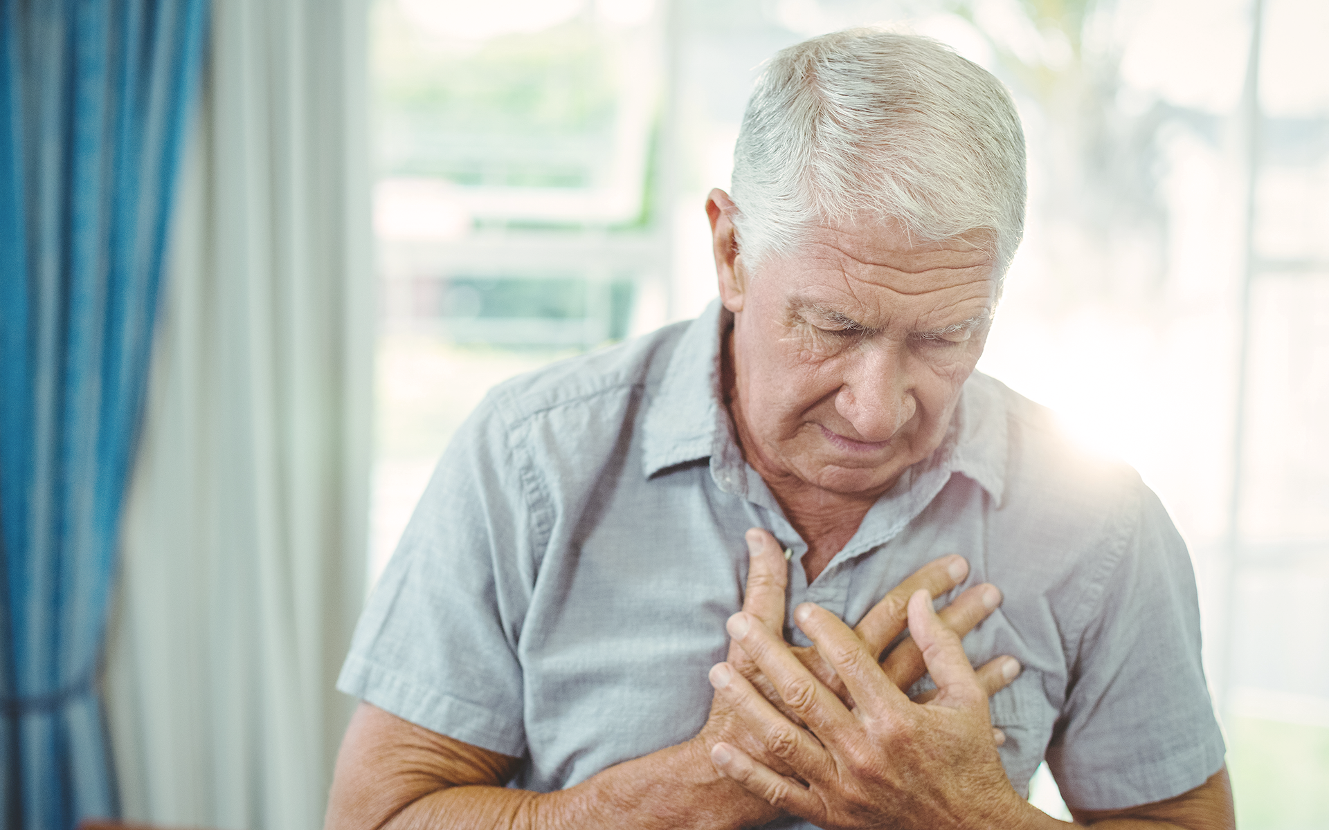 Elderly man grabs at his chest in pain.