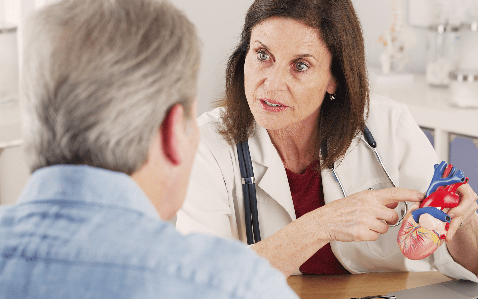 Doctor holds a plastic heart and educates man about mesothelioma.