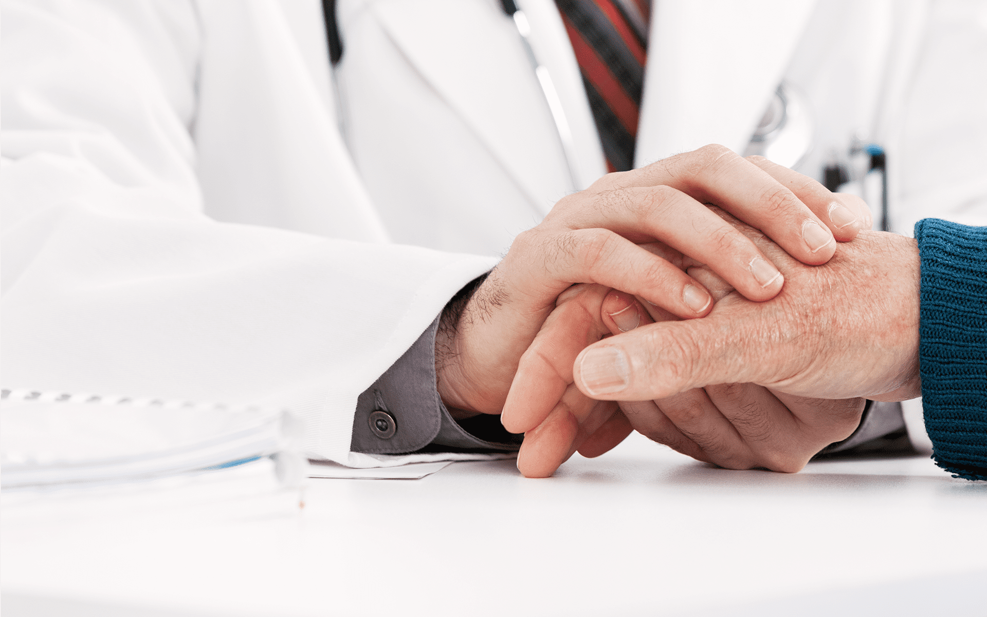 The hands of a doctor console the hands of their patient.