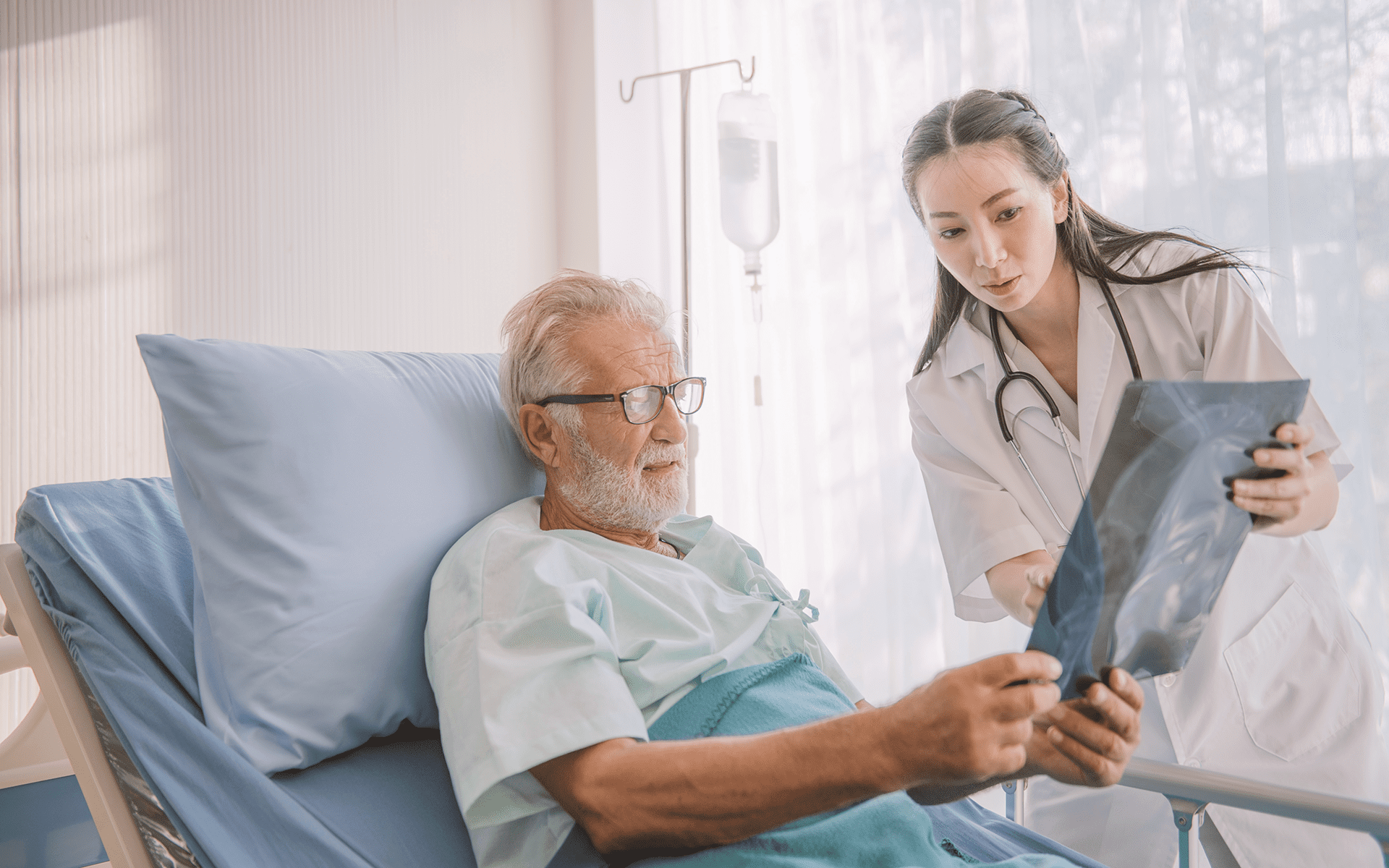 mesothelioma doctor showing her bedridden patient an x-ray.