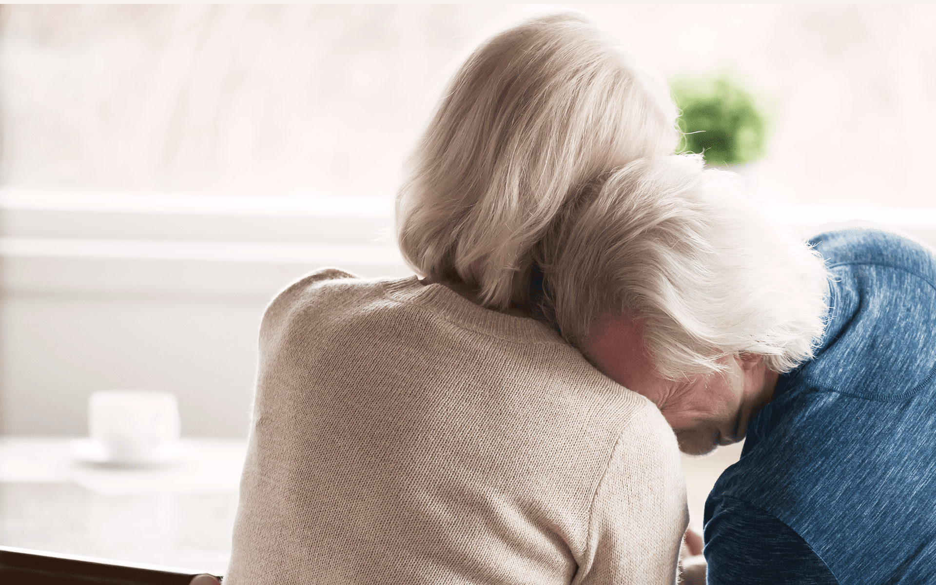 A man cries on the shoulder of his wife.