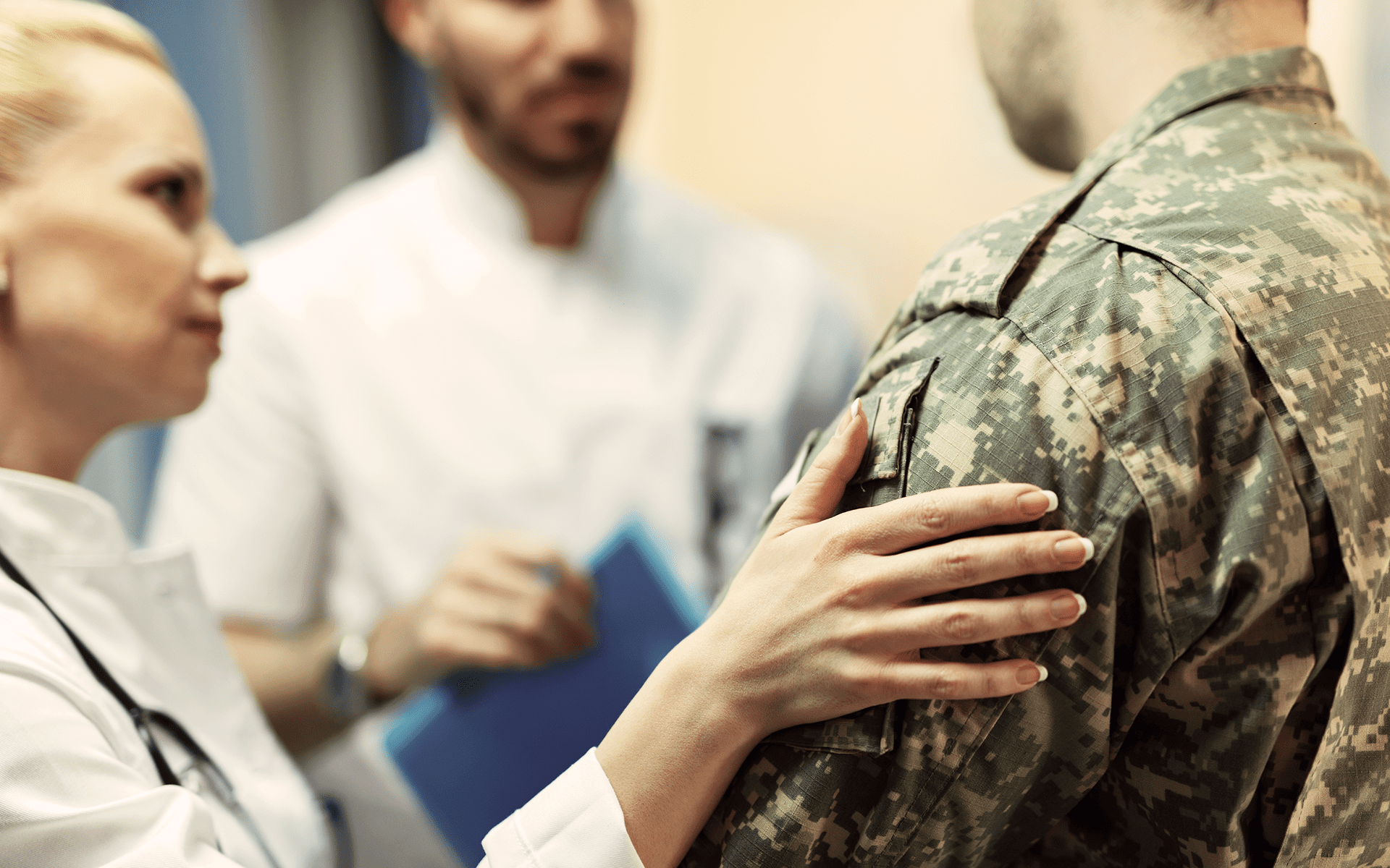 Doctor consoles veteran while they talk to another doctor.