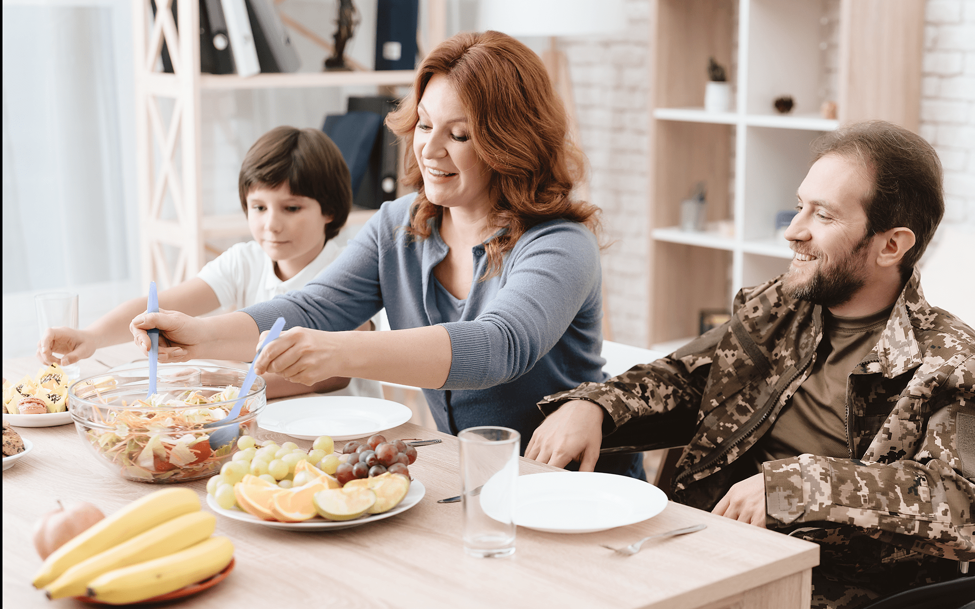 A woman prepares a salad, an assortment of fruit, and bananas for her son and veteran husband..