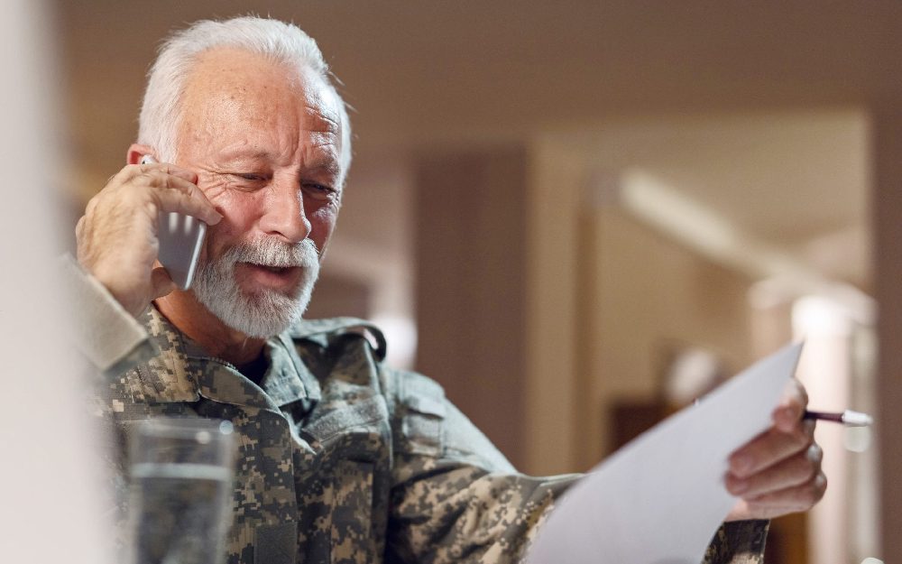 Veteran looks at document and discusses it on the cell phone.