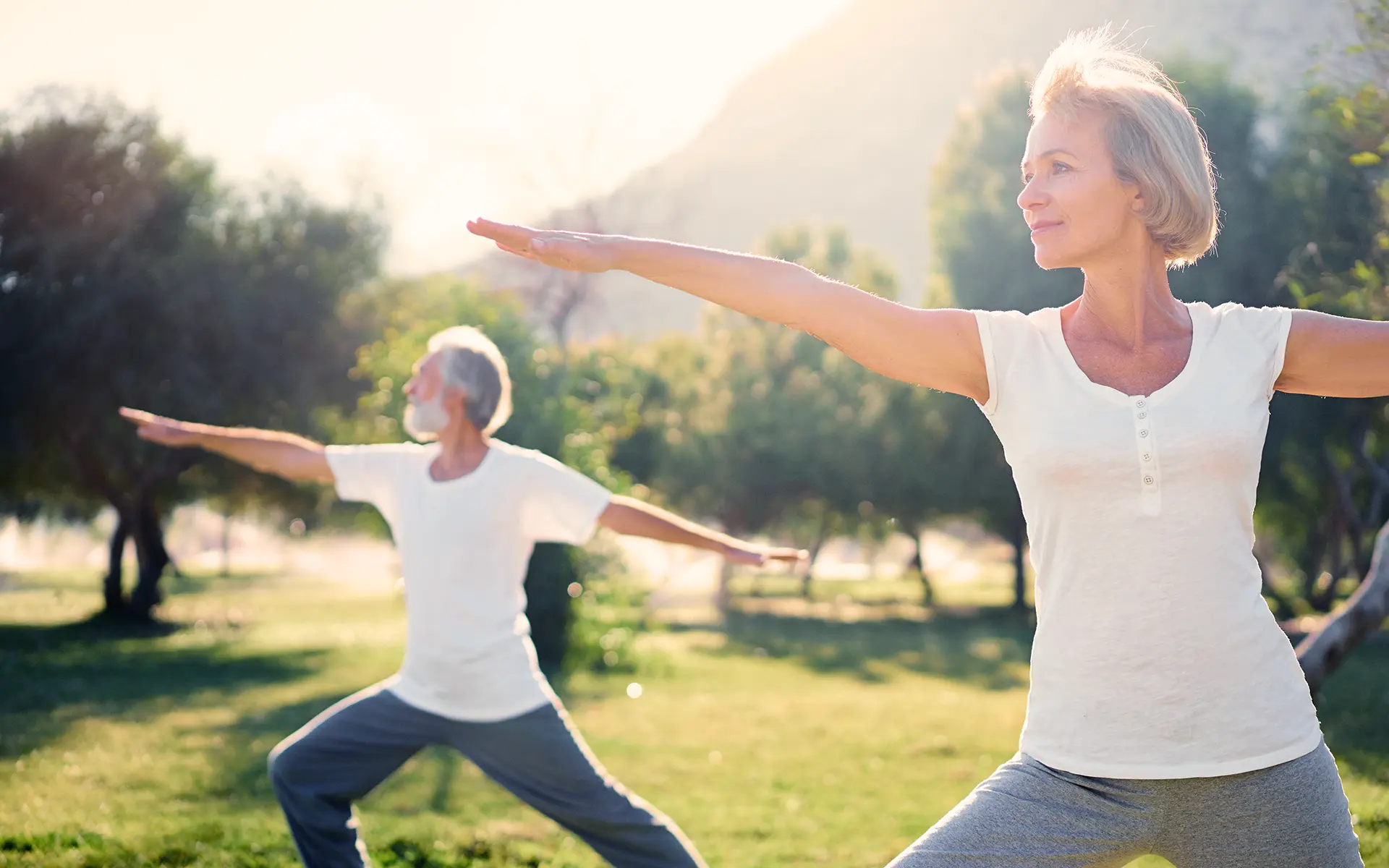 Two people doing yoga as complementary therapy in a park.