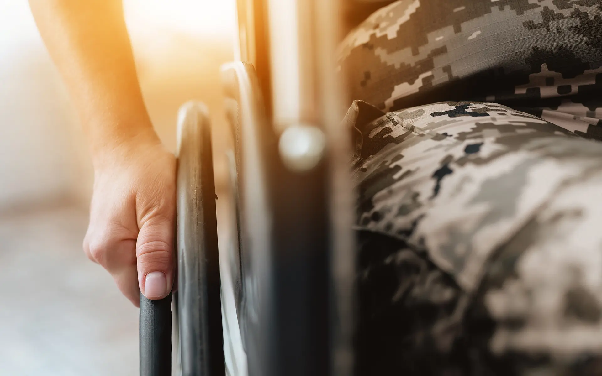 Closeup of a veteran's hand gripping the wheel on the side of their wheelchair.