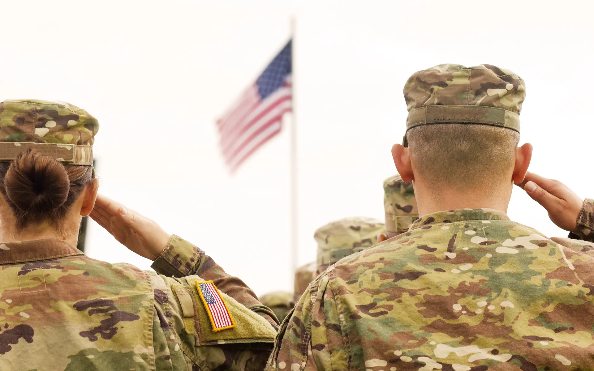 A view from behind of veterans saluting the American Flag.