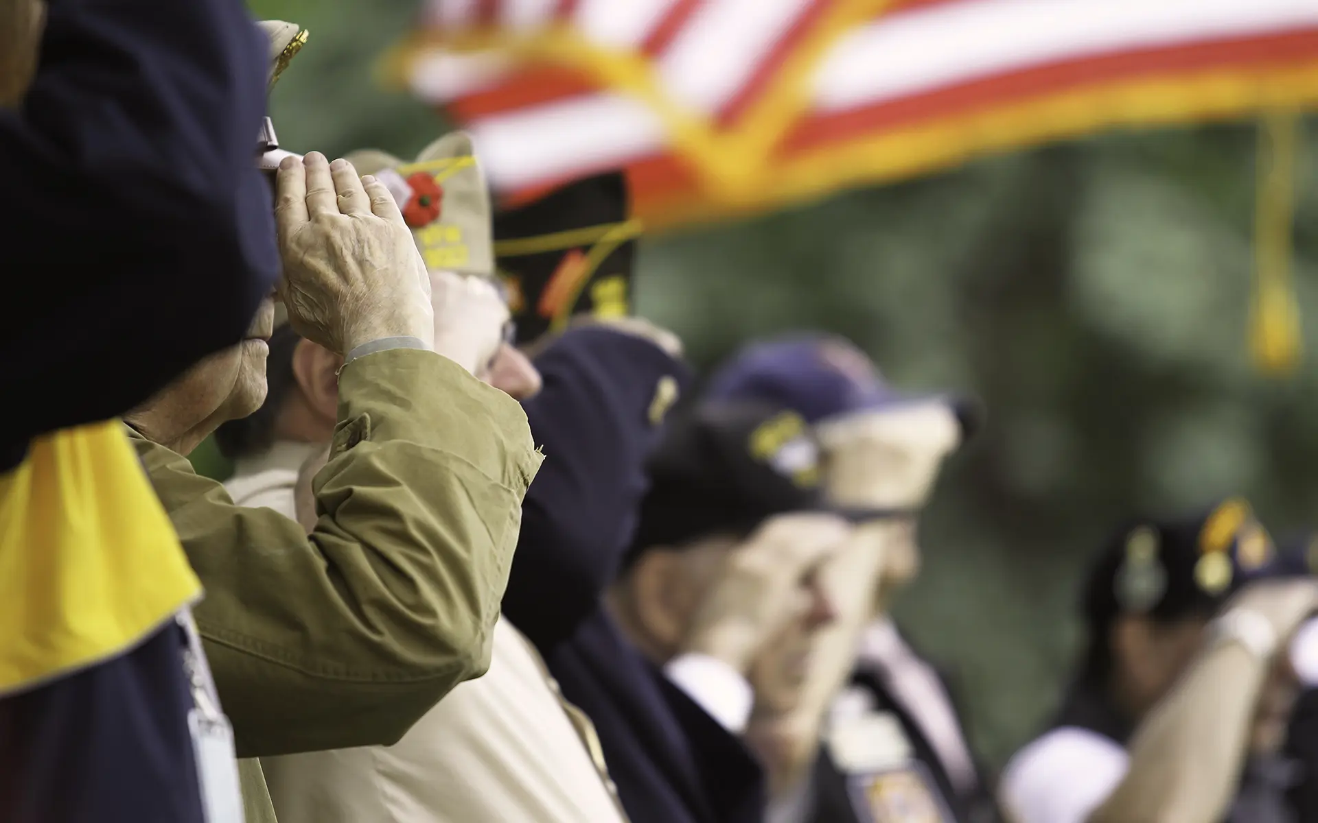 Senior veterans salute the American flag.