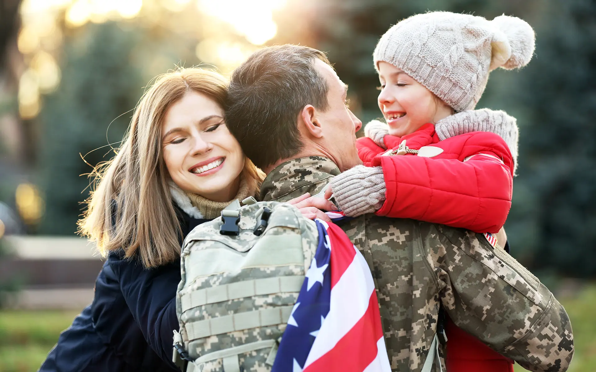 A veteran and his spouse and child embracing a warm welcome home,