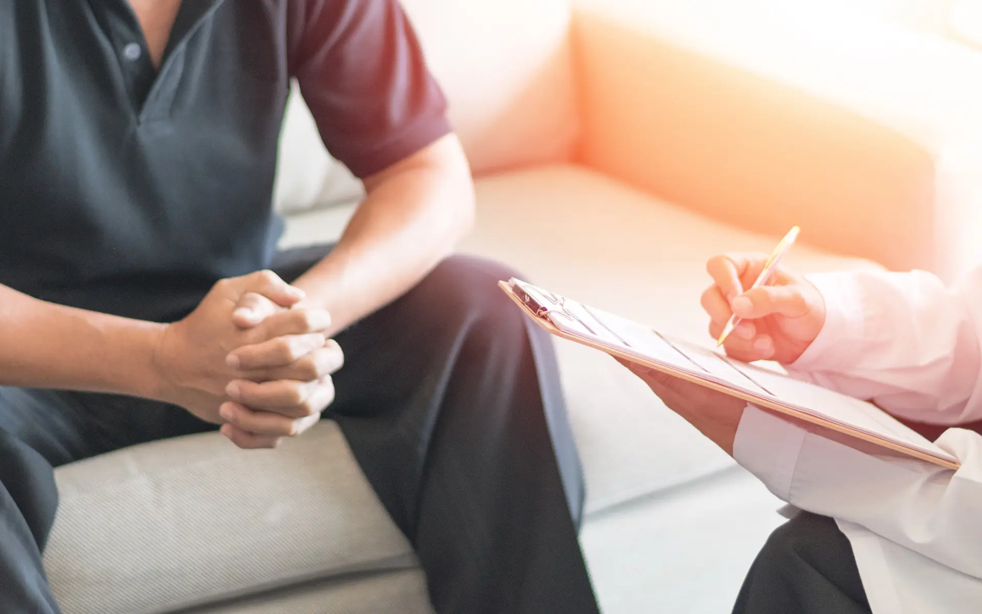 Closeup of a doctor writing on a clipboard sitting in front of their patient.