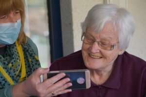 caregiver shows cell phone to the person they're providing care for