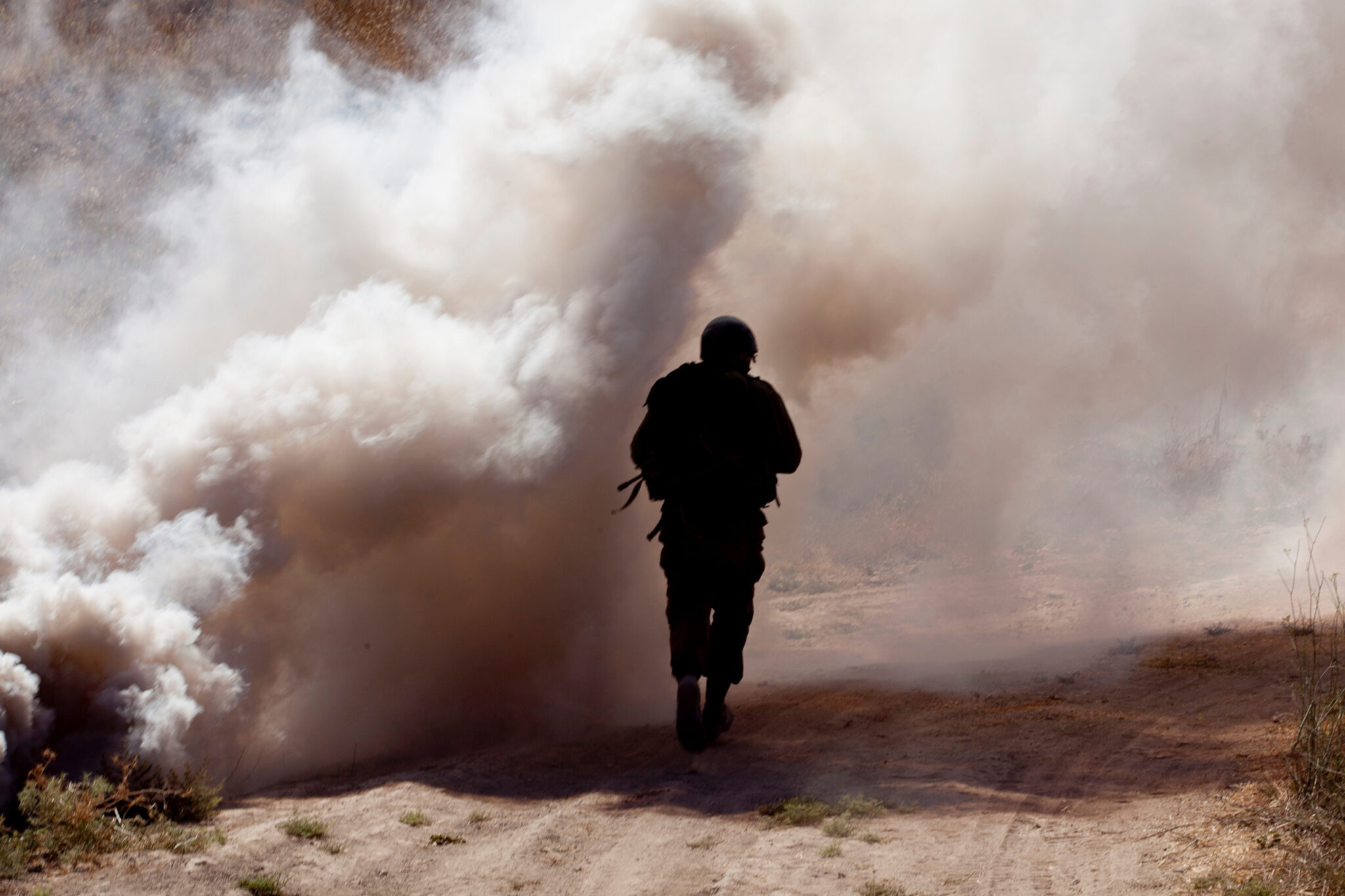 Rear View Of Soldier running through smoke and smog that may contain asbestos.