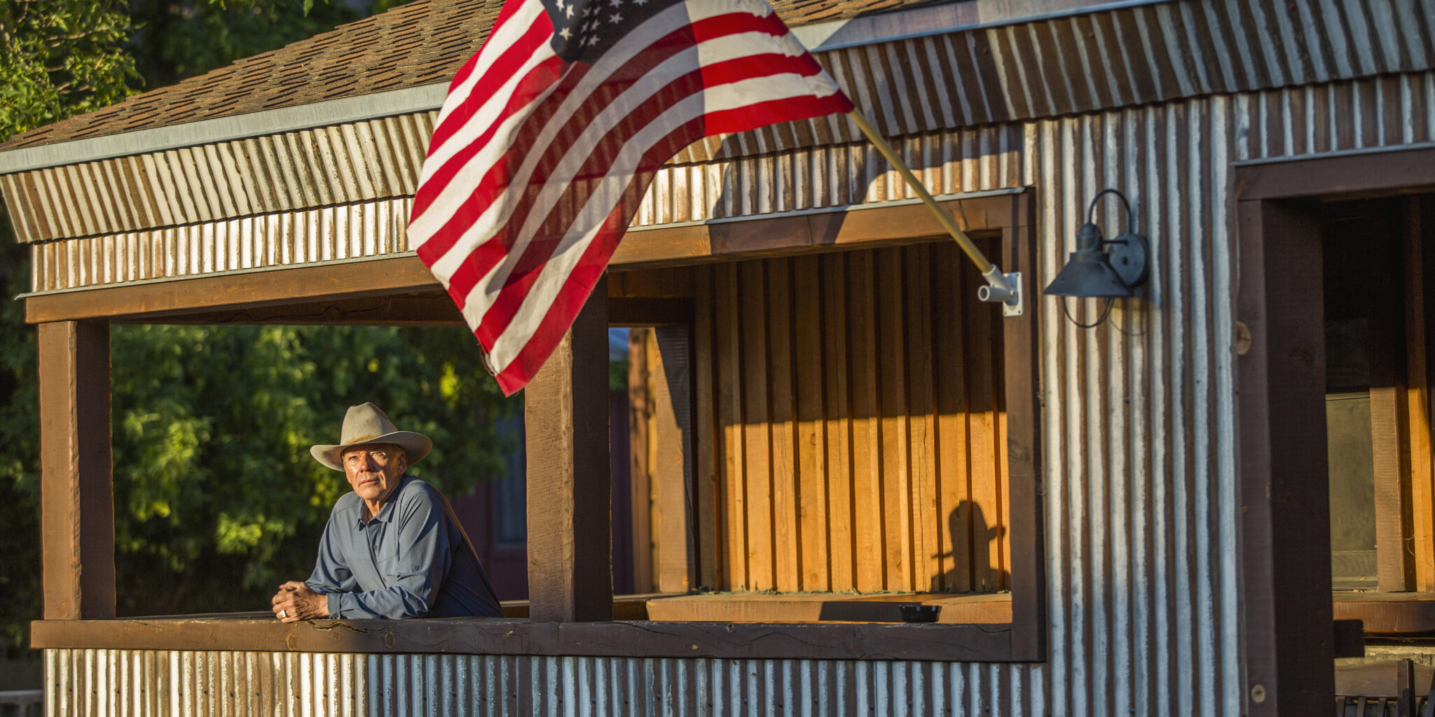 Mature cowboy on porch with American flag