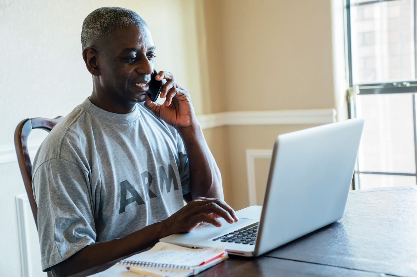 Army veteran on phone and laptop looking for online resources.