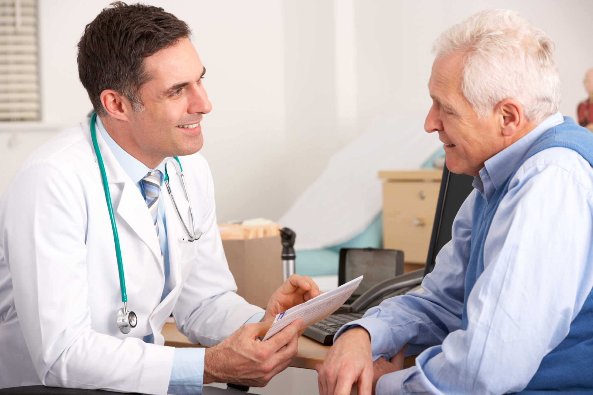 doctor talks to an elderly man in a doctor's office