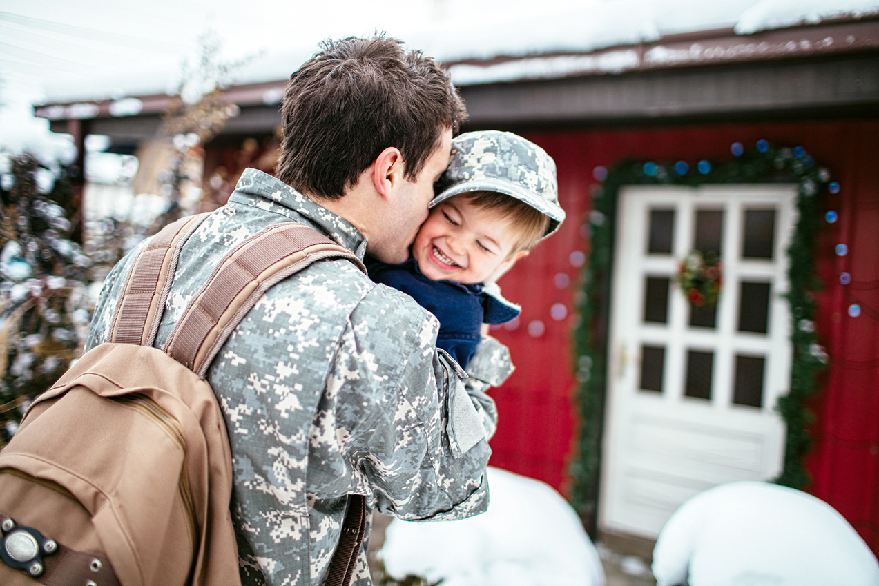 military veteran coming home for the holidays holding young child