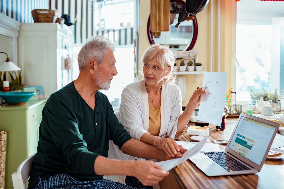 Senior Couple doing Home Finances with paperwork and laptop in front of them