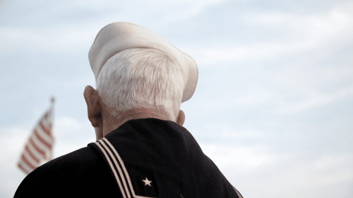 Veteran holding flag against blue sky contemplating the PACT ACT 202