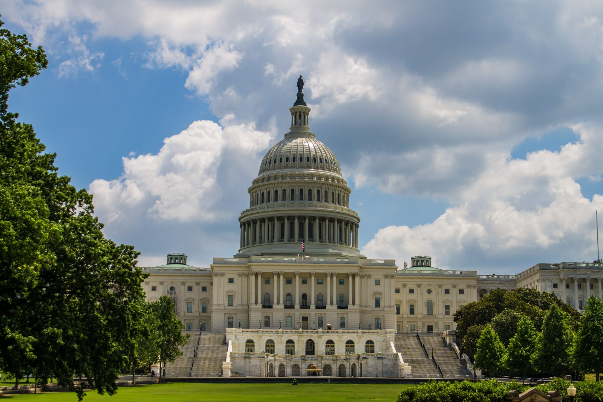 An outside photograph of the Senate building with trees and blue sky while the Senators on the inside vote on the PACT Act of 2022.