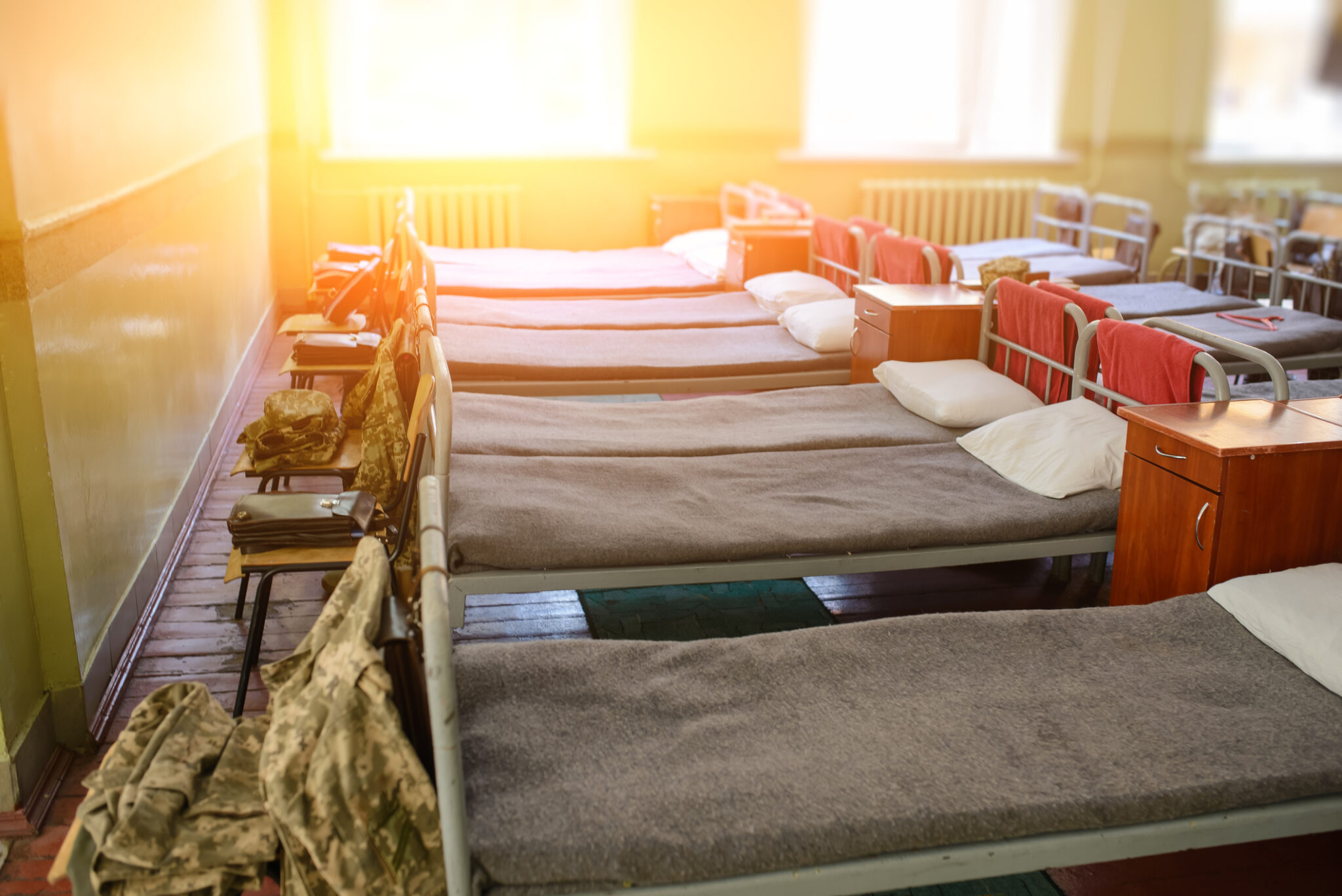 Military beds lined up in a room, similar to Fort Bragg.