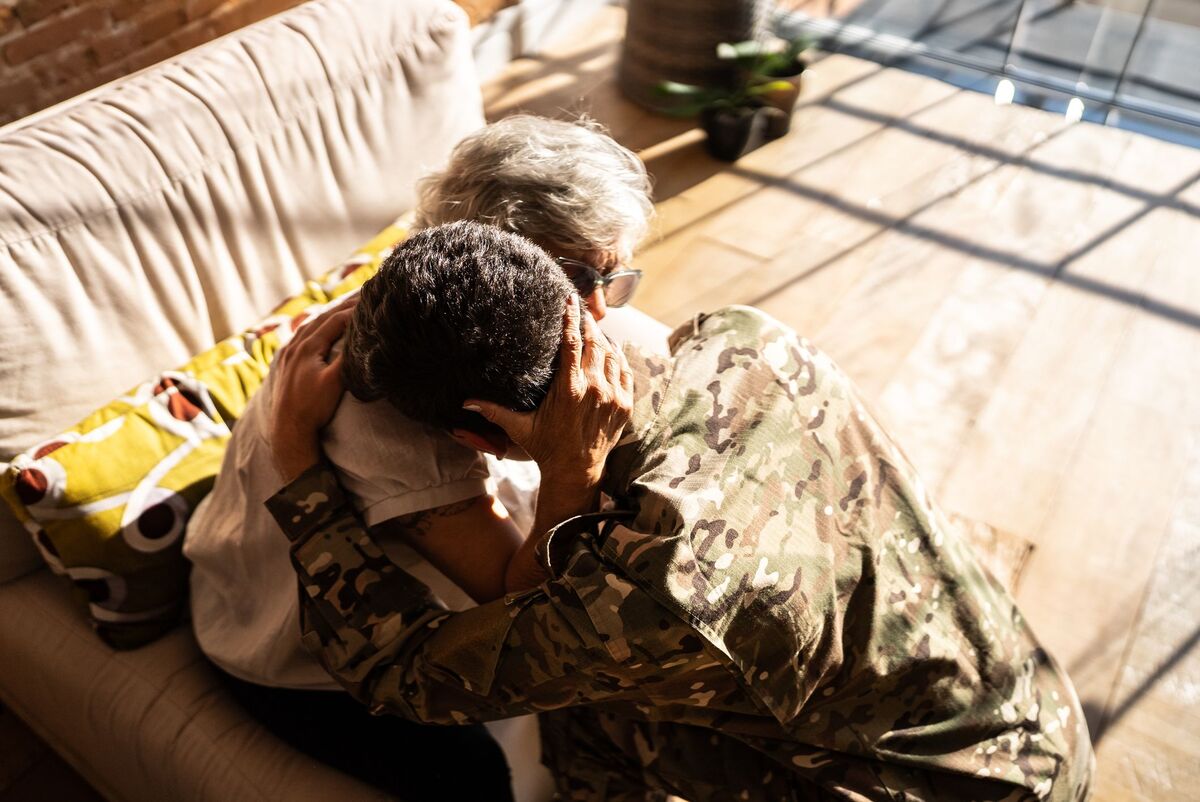 Army solider embracing his elderly grandmother at home