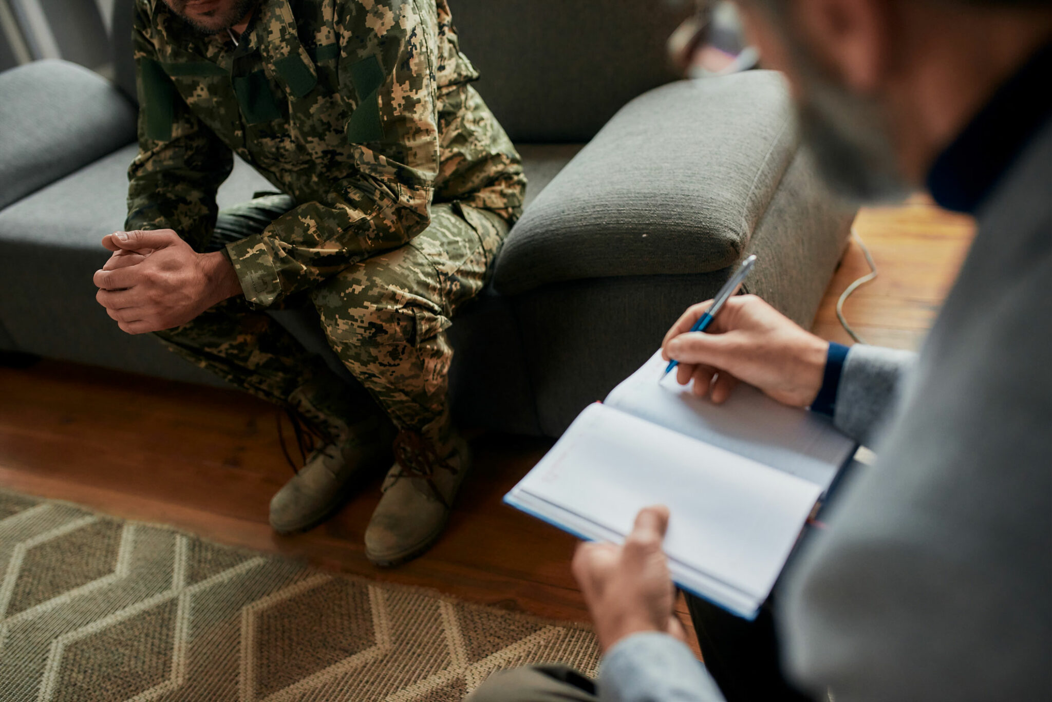 Man in military uniform sitting on a couch next to a professional